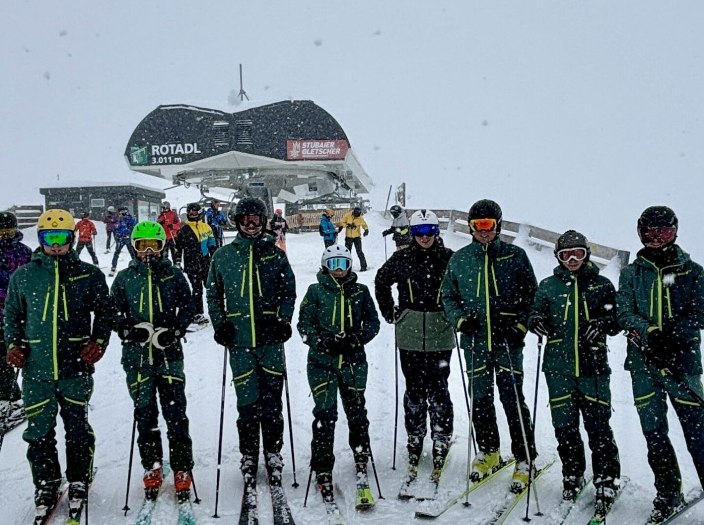 Gruppenfoto der Übungsleiter bei Schneefall am Berg, Skilift im Hintergrund